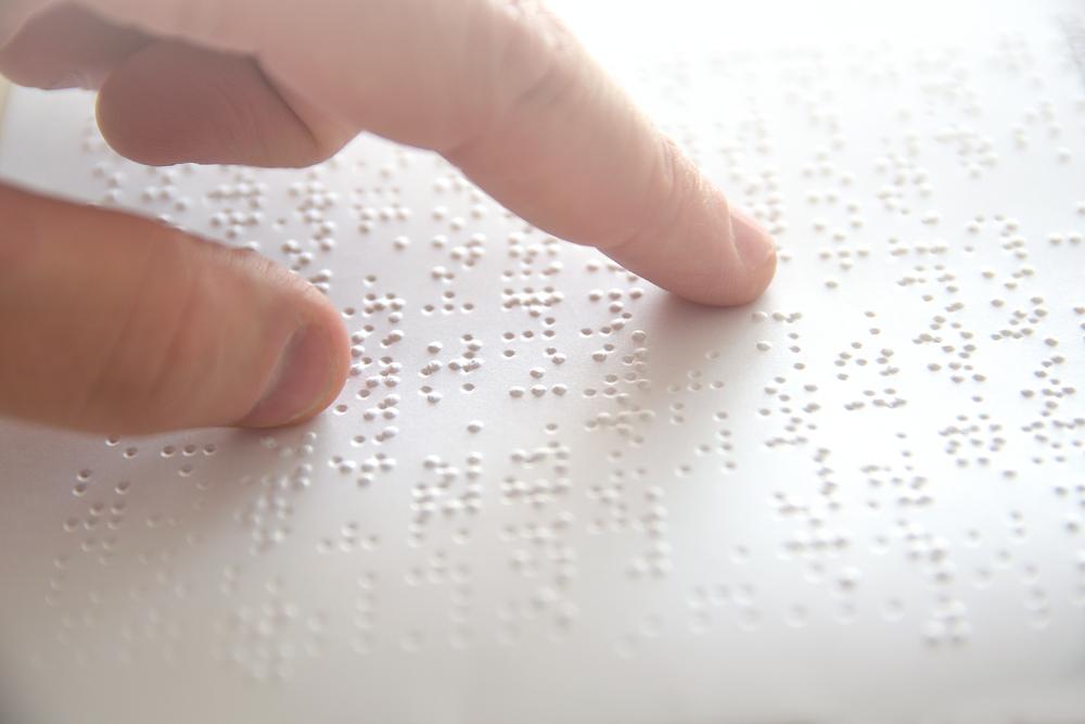 Hand of a blind person reading some braille text touching the relief. 
