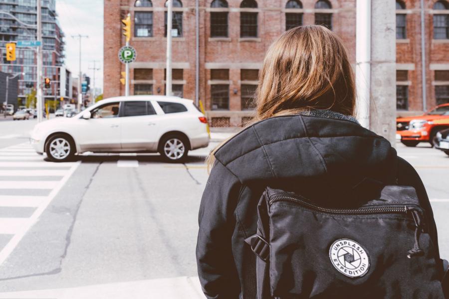 girl with backpack trying to cross street